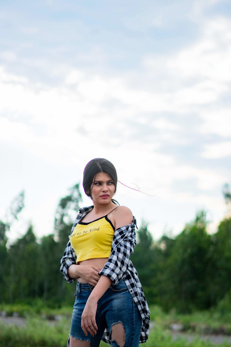 Standing Woman Wearing A Bright Yellow Tank Top, Jeans And A Checked Shirt