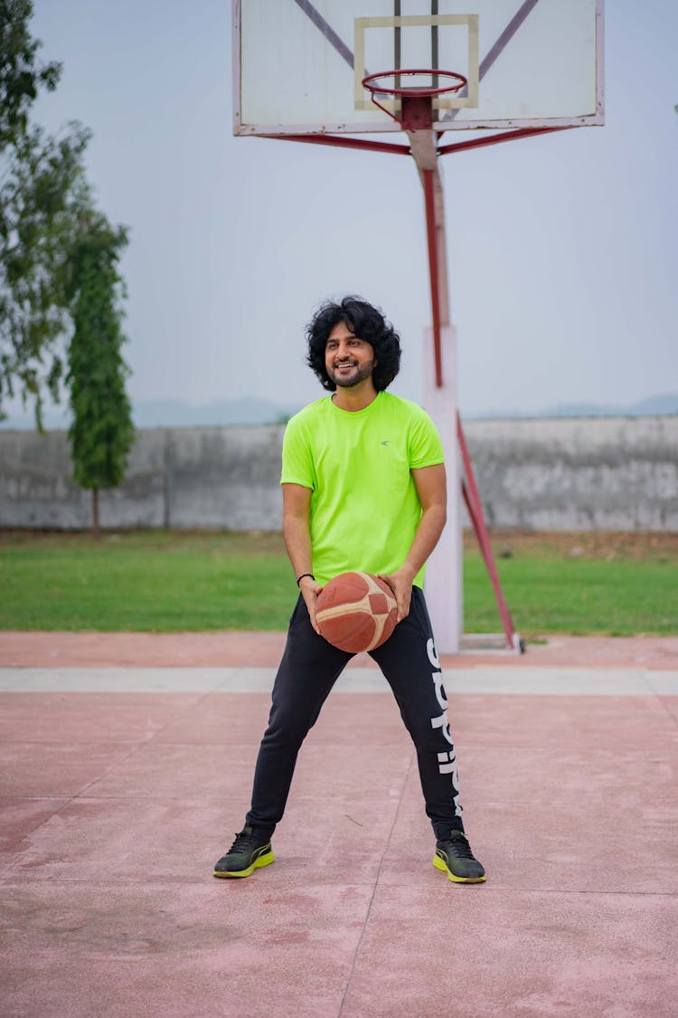 Man In Green Crew Neck T-shirt And Black Pants Holding A Ball