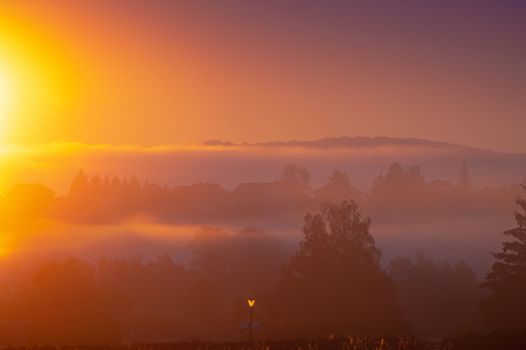 A captivating sunrise over a foggy landscape with vibrant warm colors and silhouettes.