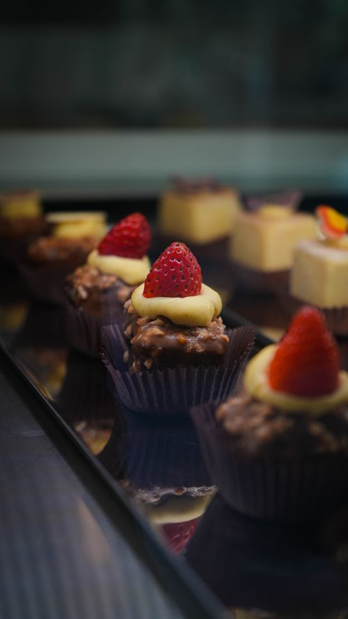 Free Tempting chocolate desserts with strawberry toppings displayed in a bakery setting. Stock Photo