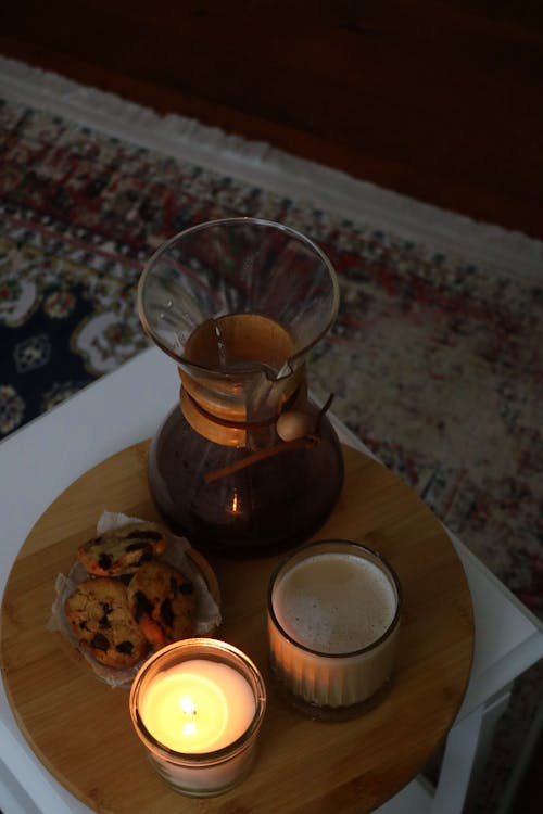 Glass of Chocolate Drink Beside a Bowl of Cookies and Lighted Candle