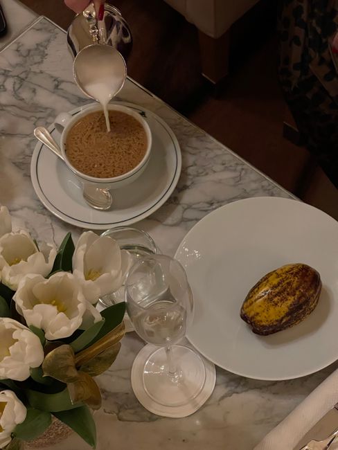 Marble table setting in Paris with coffee being poured, a pastry, and white flowers.
