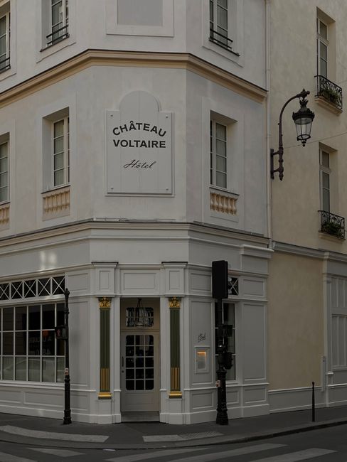 Discover the classic facade of Château Voltaire Hotel on a quiet city street corner, showcasing French architecture.