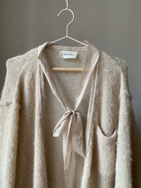Soft cream sweater displayed on a hanger indoors, perfect for cozy comfort.