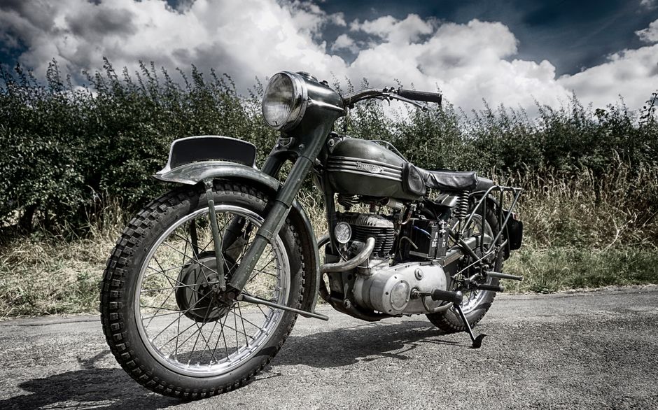 Classic military motorcycle displayed on a country road, exuding retro charm.