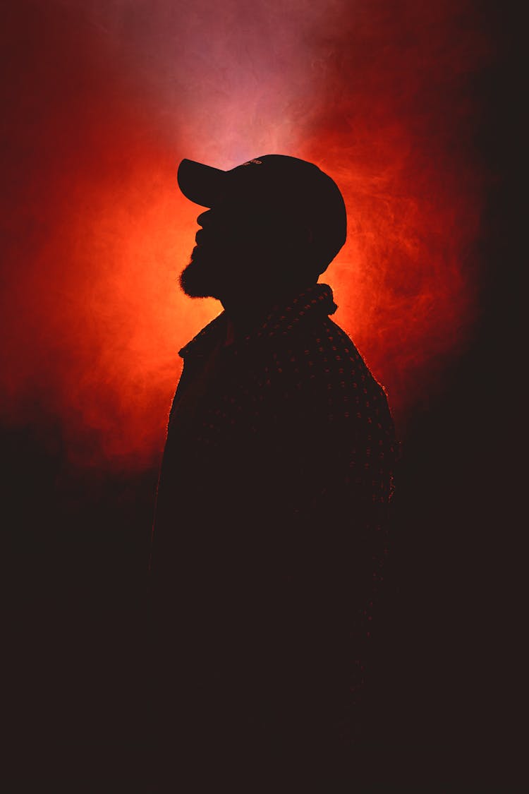 Silhouette Of A Man Wearing A Cap In Red Lighting And Smoke 