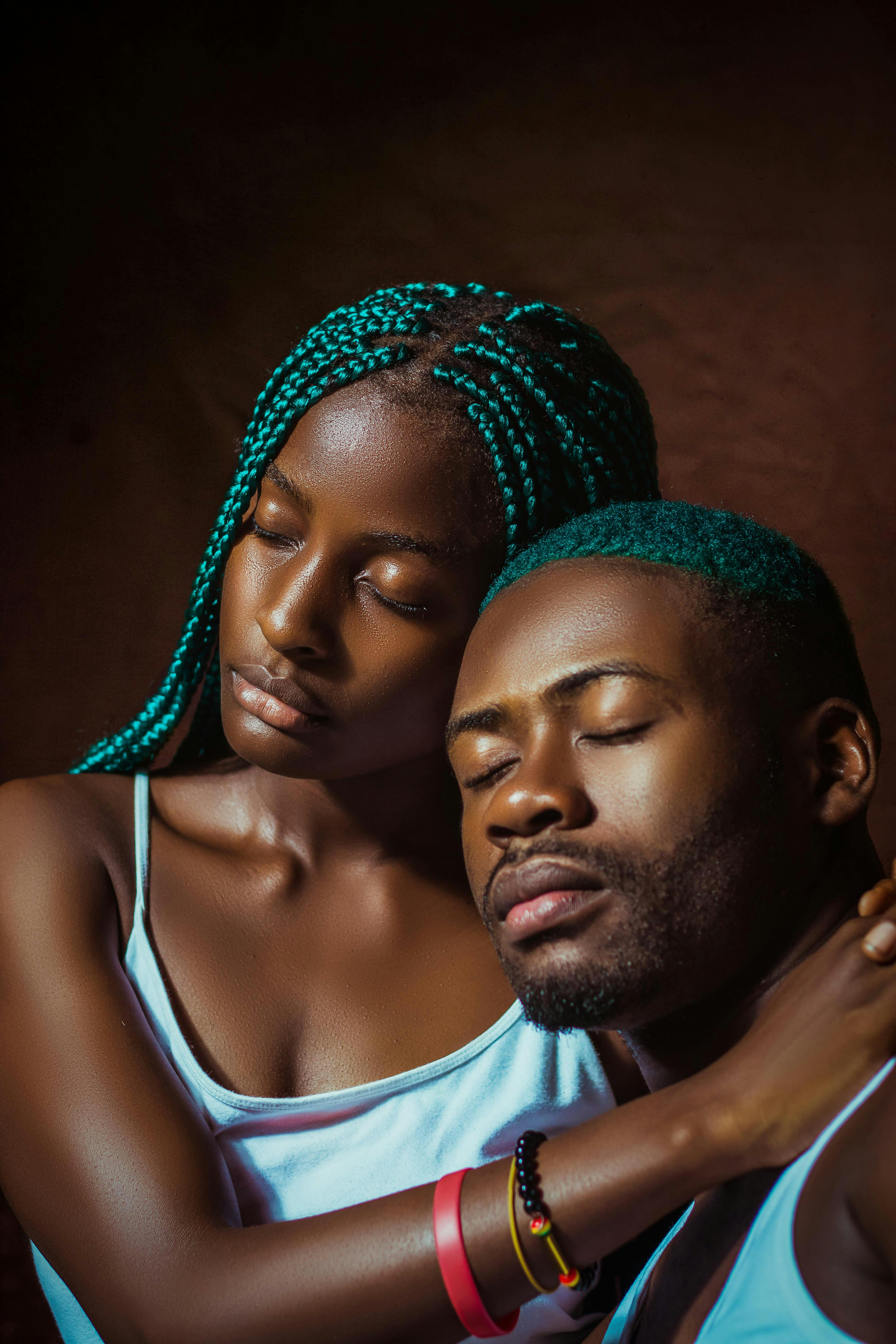 Intimate portrait of a couple embracing with eyes closed, showcasing blue braided hair.