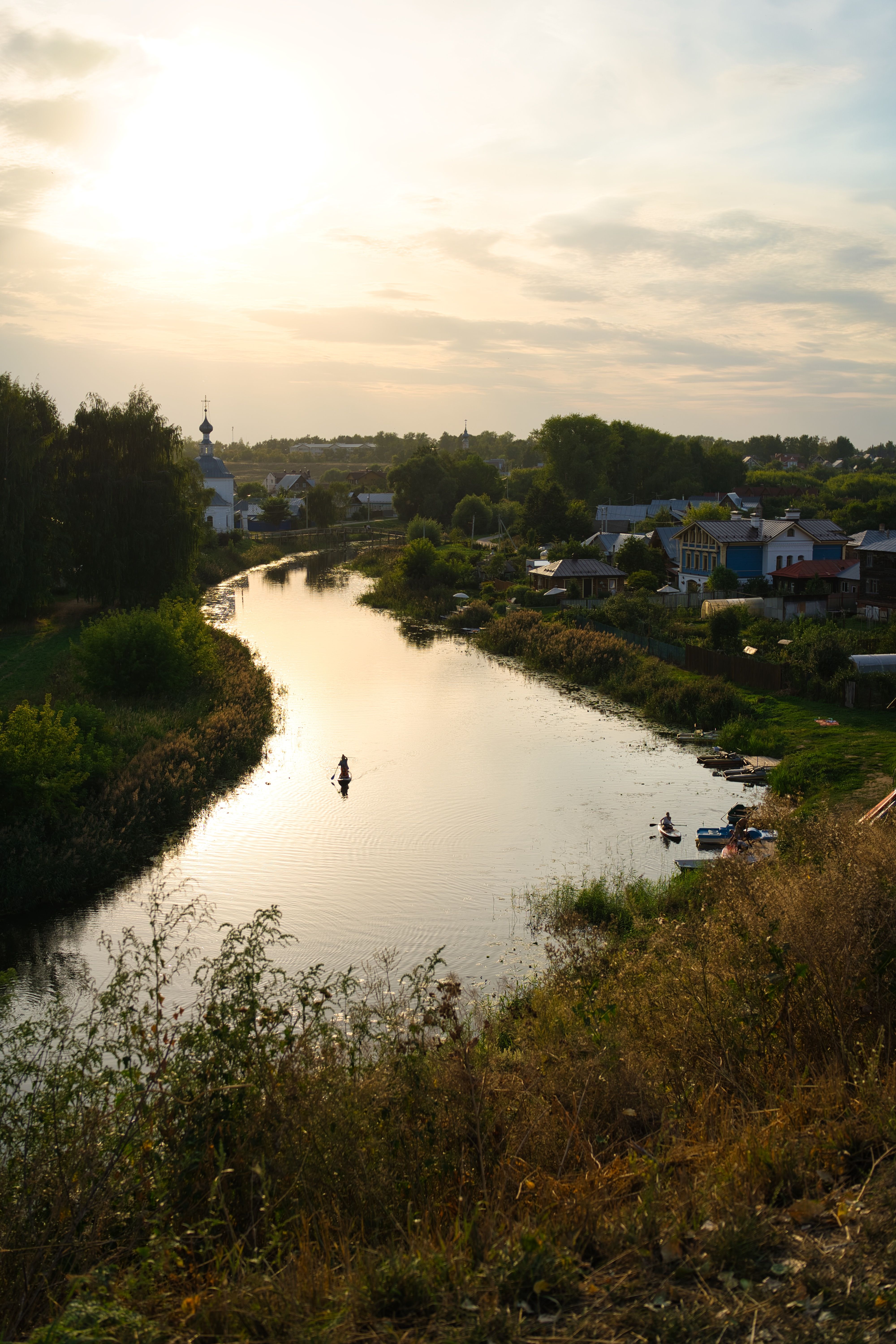 Peaceful rural scene with river and houses at sunset in Suzdal, Russia.