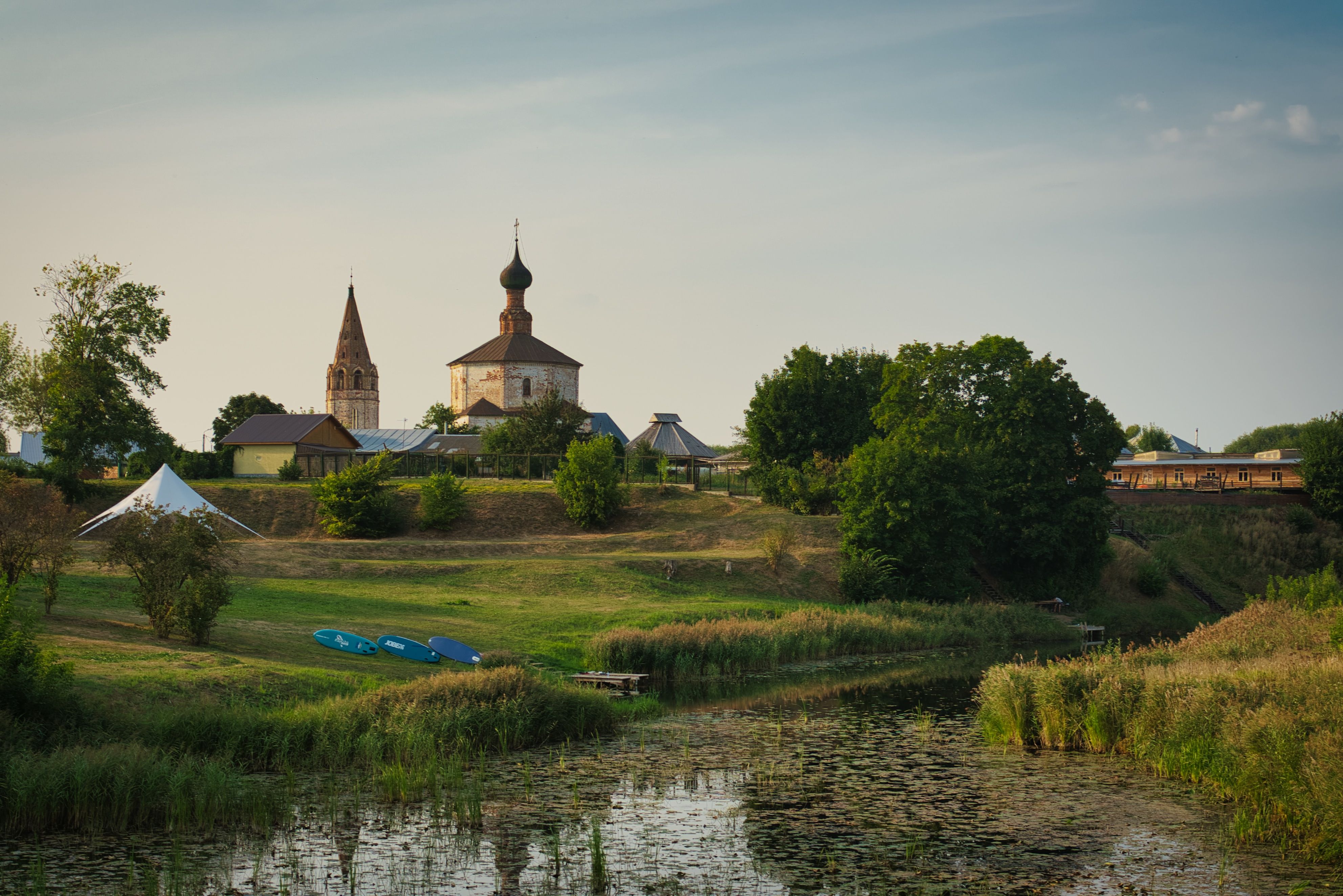 Scenic view of Suzdal with a church and lush greenery under a bright sky.