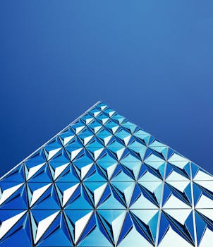 现代建筑引人注目的形象中，几何玻璃板反射出清澈的蓝天