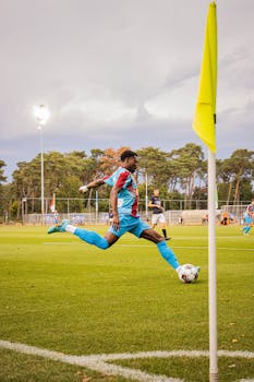 Soccer player striking the ball during a game on a green field under bright lights.