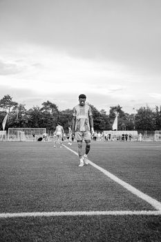 Black and white photo of a soccer player walking on a field in Lommel, Belgium.