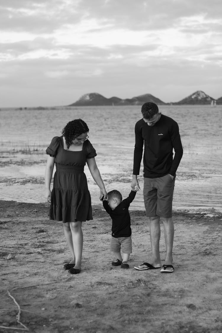 Grayscale Photo Of Family Standing On Beach