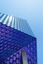 低角度视角下的现代建筑，其几何玻璃板反射着蓝天