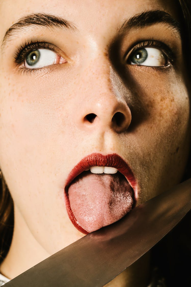 Woman With Red Lipstick Licking A Knife