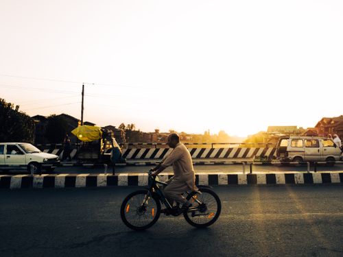 Free Cyclist navigating through city traffic during a stunning sunset, capturing the essence of urban life. Stock Photo