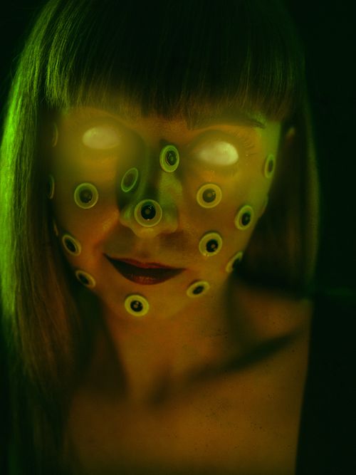 Free Surreal image of a woman with glowing eyes and eyeball stickers, creating a spooky and eccentric appearance. Stock Photo