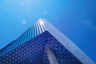 这座高大的玻璃建筑以几何图案为特色，映衬着清澈的蓝天，体现了现代建筑的设计风格