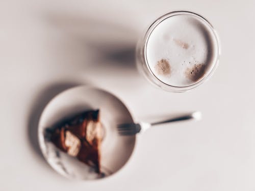 Top View of a Piece of Cake on a Plate and a Milky Coffee