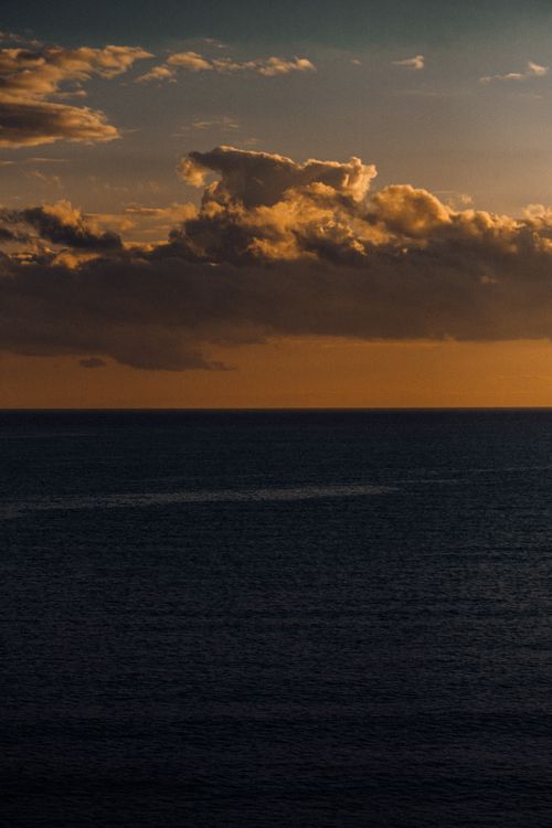 Free Serene ocean view at sunset with dramatic clouds and vibrant colors. Stock Photo