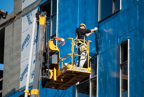 Worker Insulating a Building from the Skylift Basket