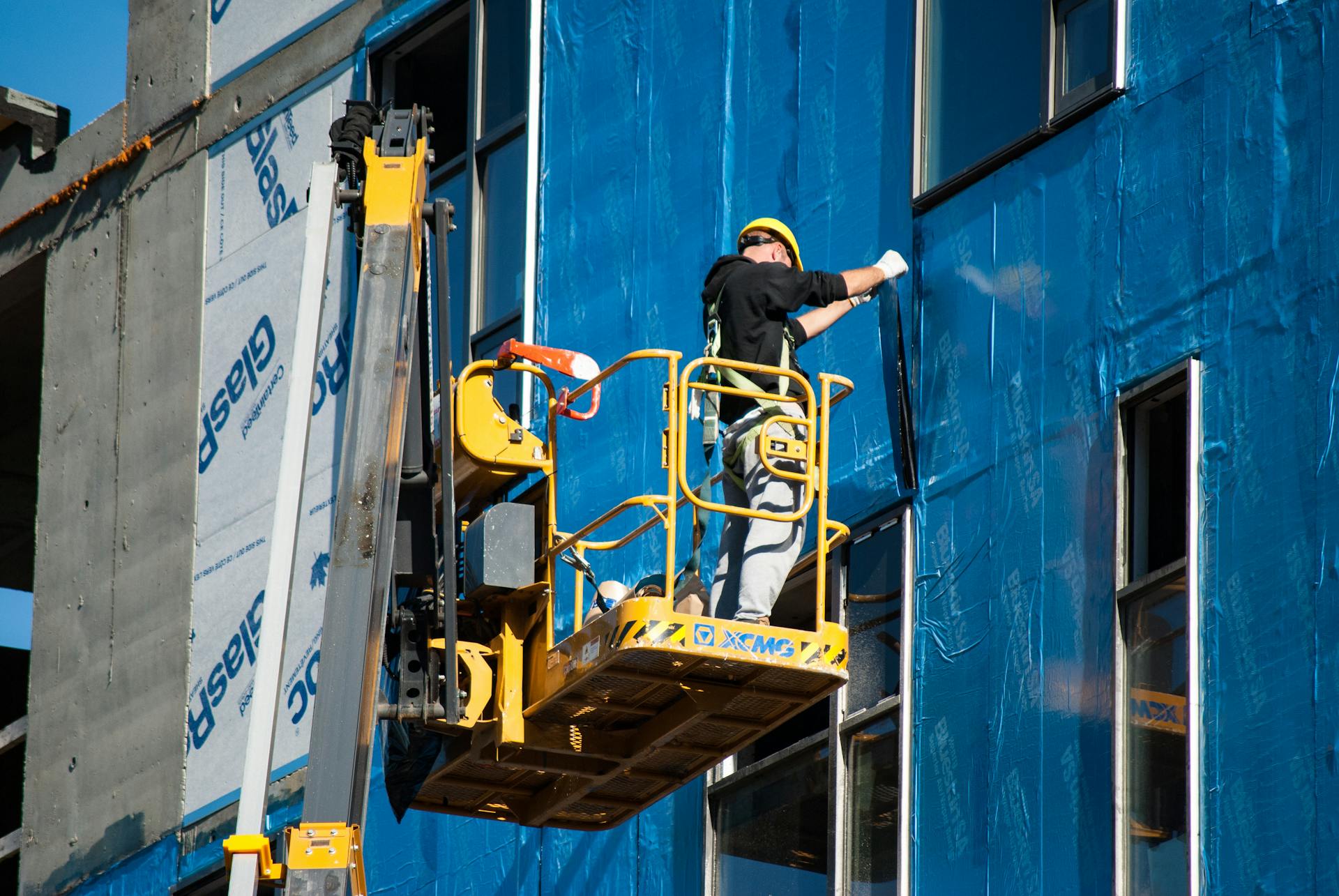 Man on skylift installing facade on building for construction project.