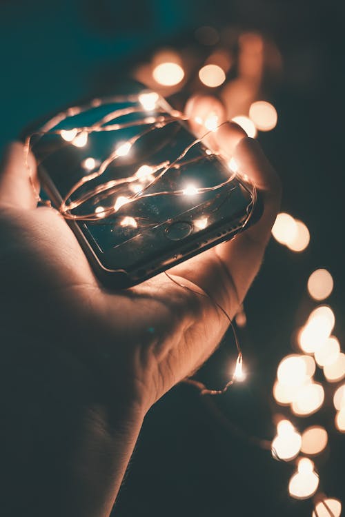 Person Holding Space Gray Iphone 6 With String Lights during Nighttime