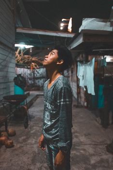 深夜，一个年轻人站在昏暗的小巷里，抬头沉思