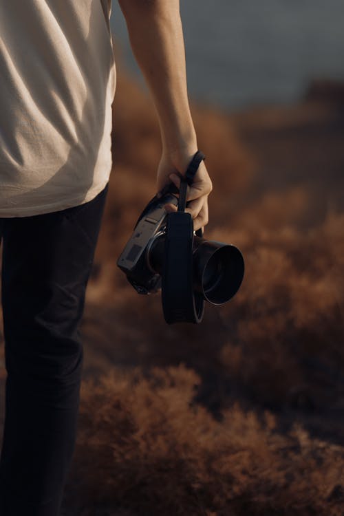 Person in White Shirt Holding Black Dslr Camera