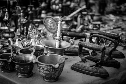 A black and white photo featuring a collection of antique irons and cups, evoking nostalgia.