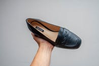 A Black Leather Shoe on a Person's Hand