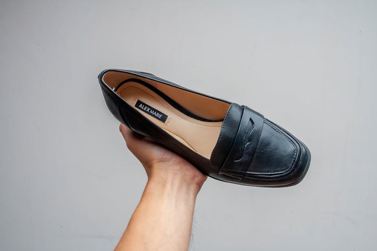 A Black Leather Shoe On A Person's Hand