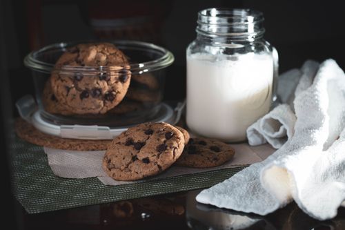 Free A cozy afternoon snack setup featuring chocolate chip cookies and a glass of milk. Stock Photo