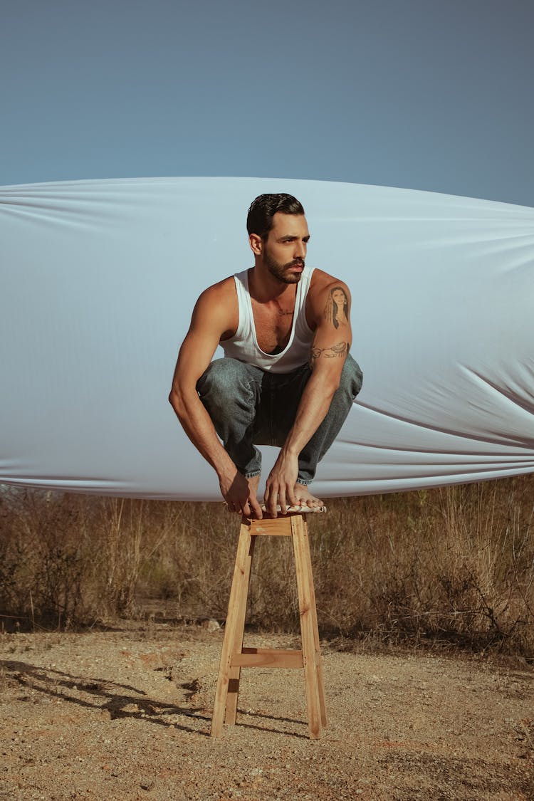 Man Crouching On Stool