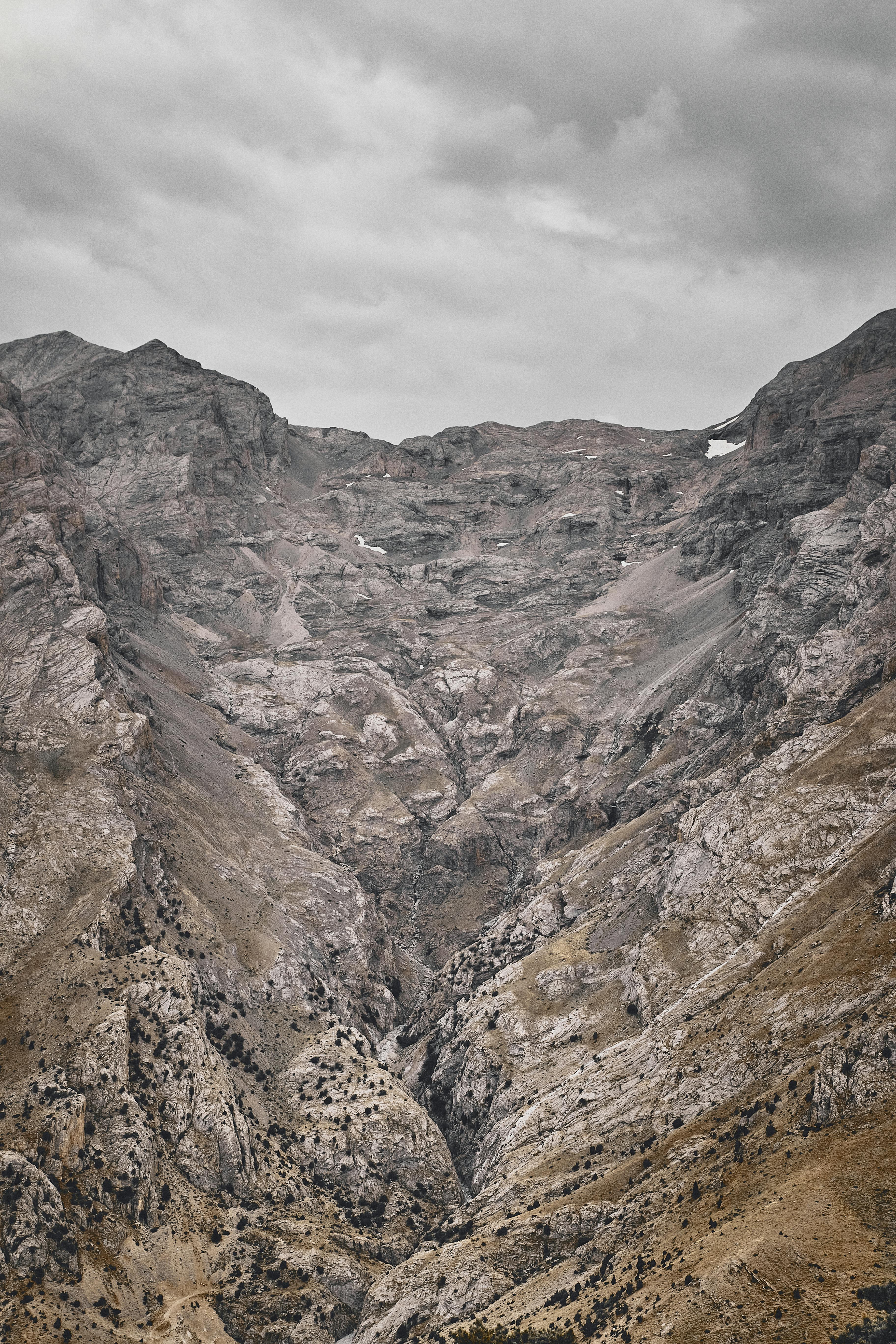 Prescription Goggle Inserts - Majestic rocky mountain landscape with snow patches under a cloudy sky.