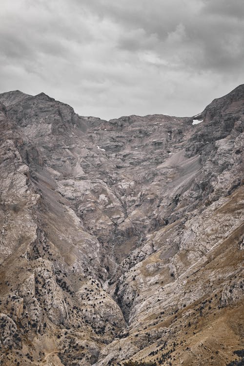 Brown and Gray Rocky Mountain Under White Cloudy Sky