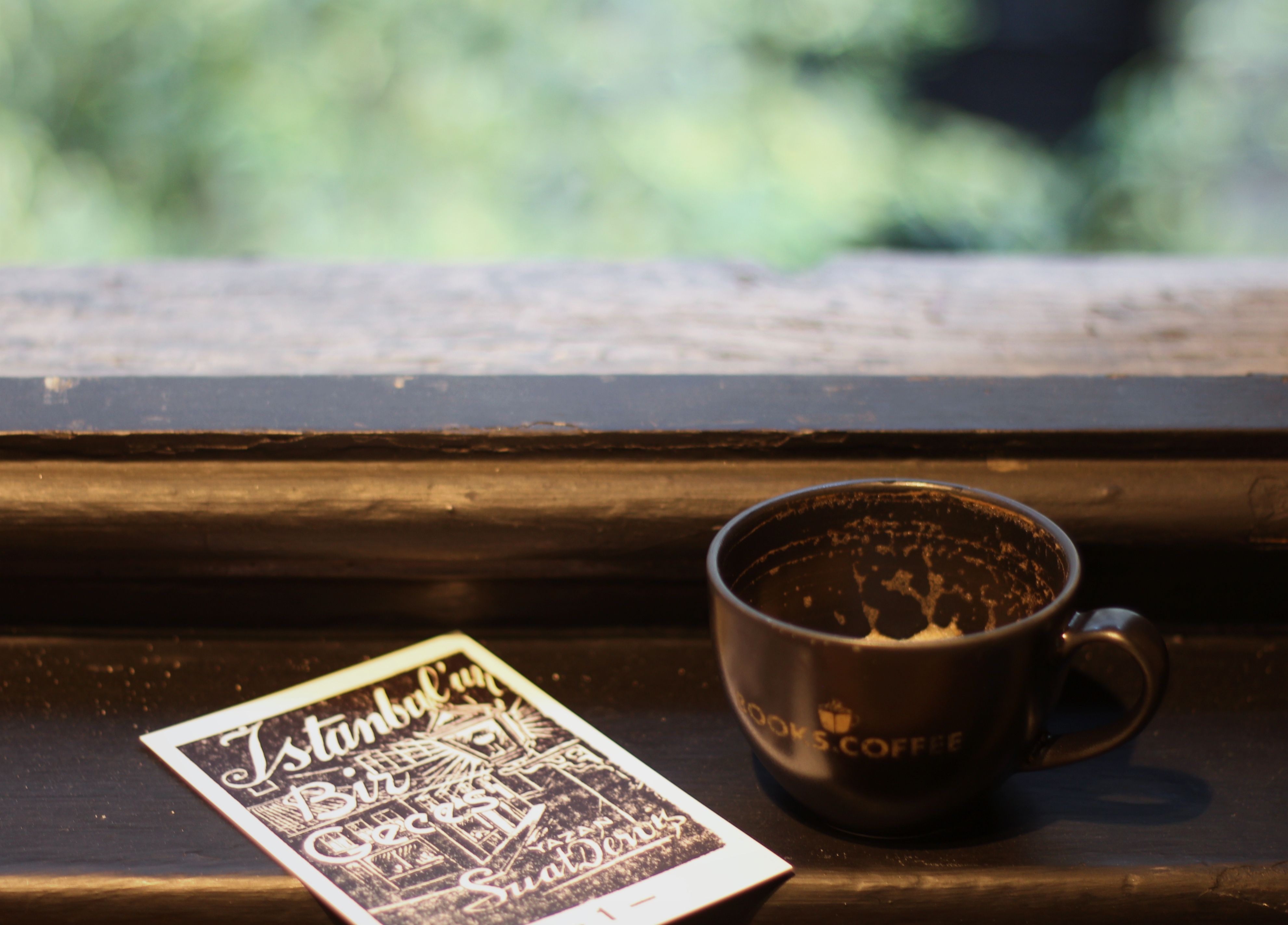 Empty coffee cup and Istanbul postcard on a windowsill create a nostalgic vibe.