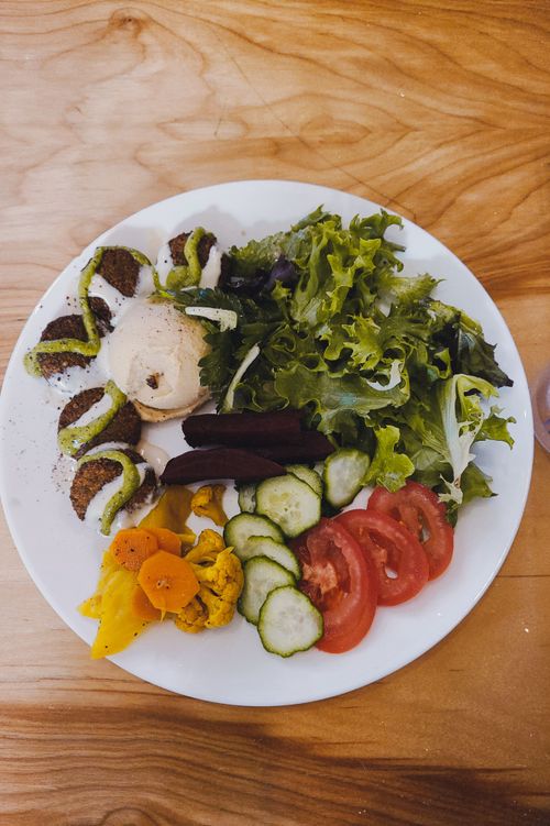 Free Top view of a fresh vegetable salad with falafel and hummus on a wooden table. Stock Photo