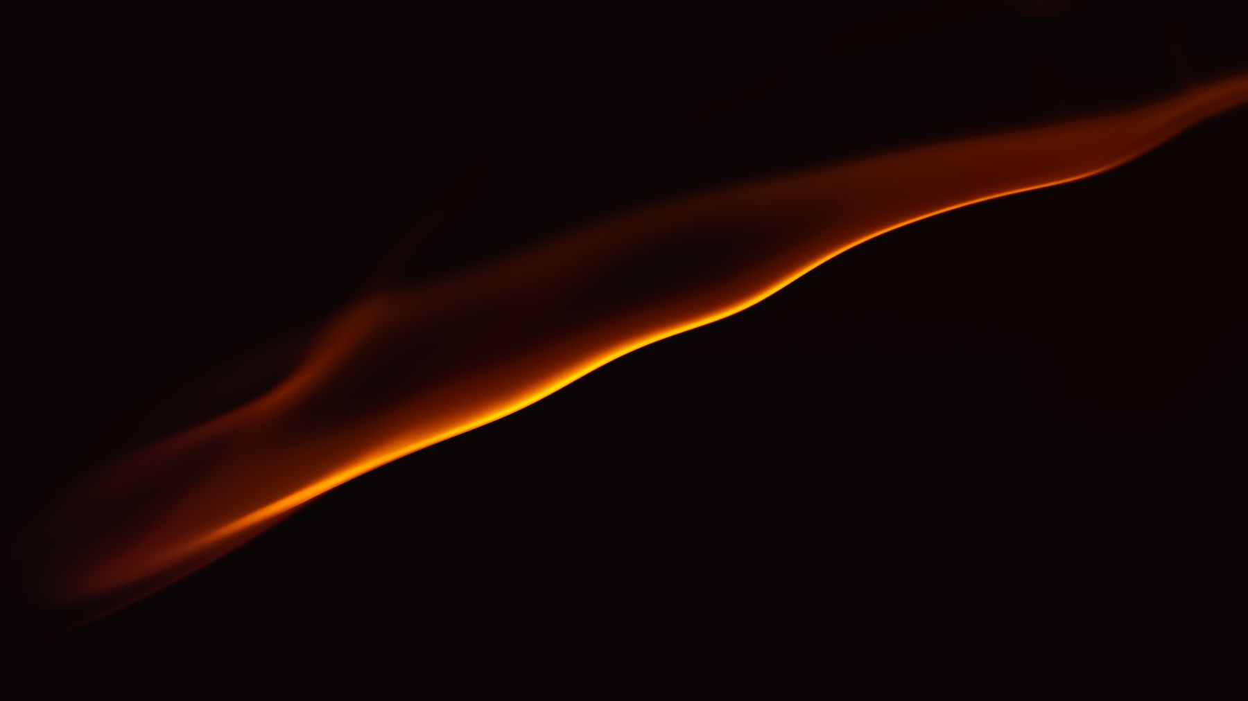 Abstract curved flame of amber light glowing on a dark ground — photo by Marek Piwnicki on Pexels