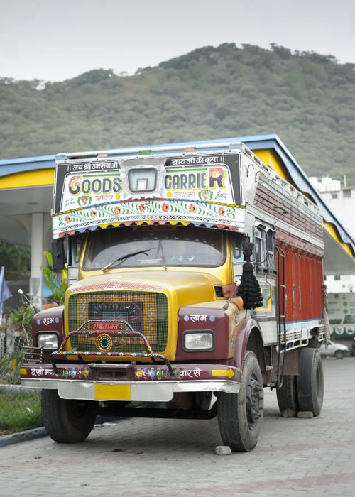 Free Colorful goods carrier truck parked at a gas station in Udaipur, India, with scenic mountain backdrop. Stock Photo