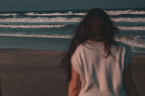A Woman in White Shirt Walking on the Beach