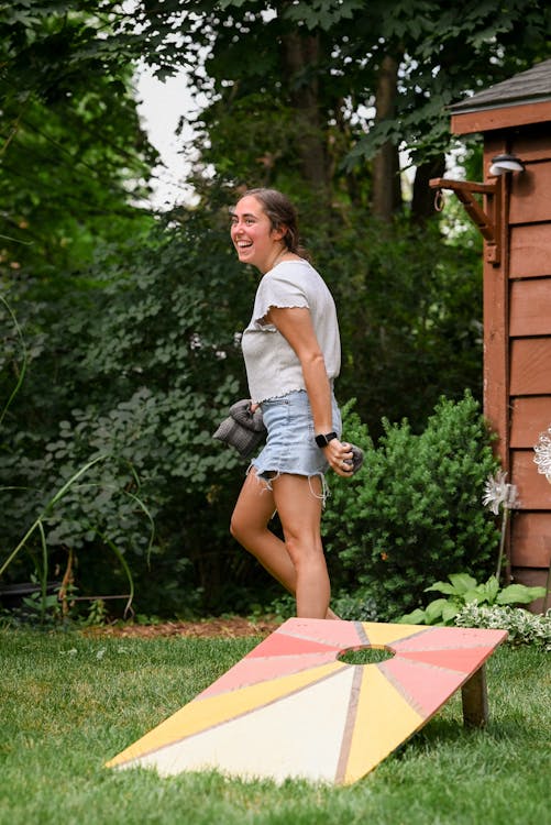 Free A Woman Playing Bean Bag Toss in the Backyard Stock Photo