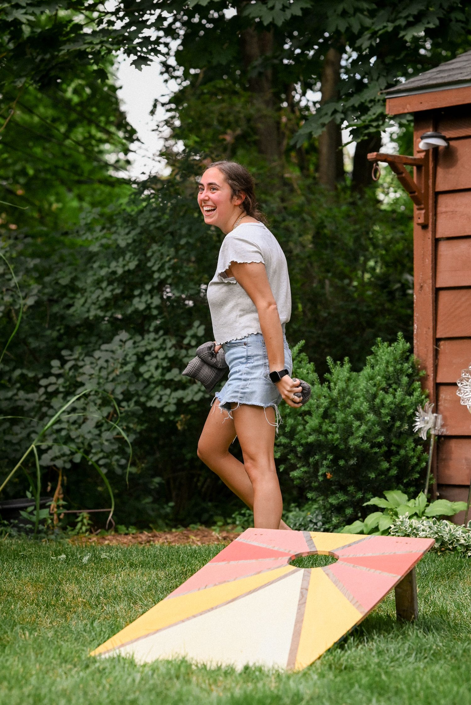 Guest enjoying a beanbag toss game at a backyard gathering