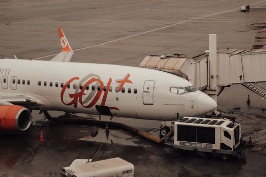 GOL Airlines aircraft connected to jet bridge at a wet airport terminal.