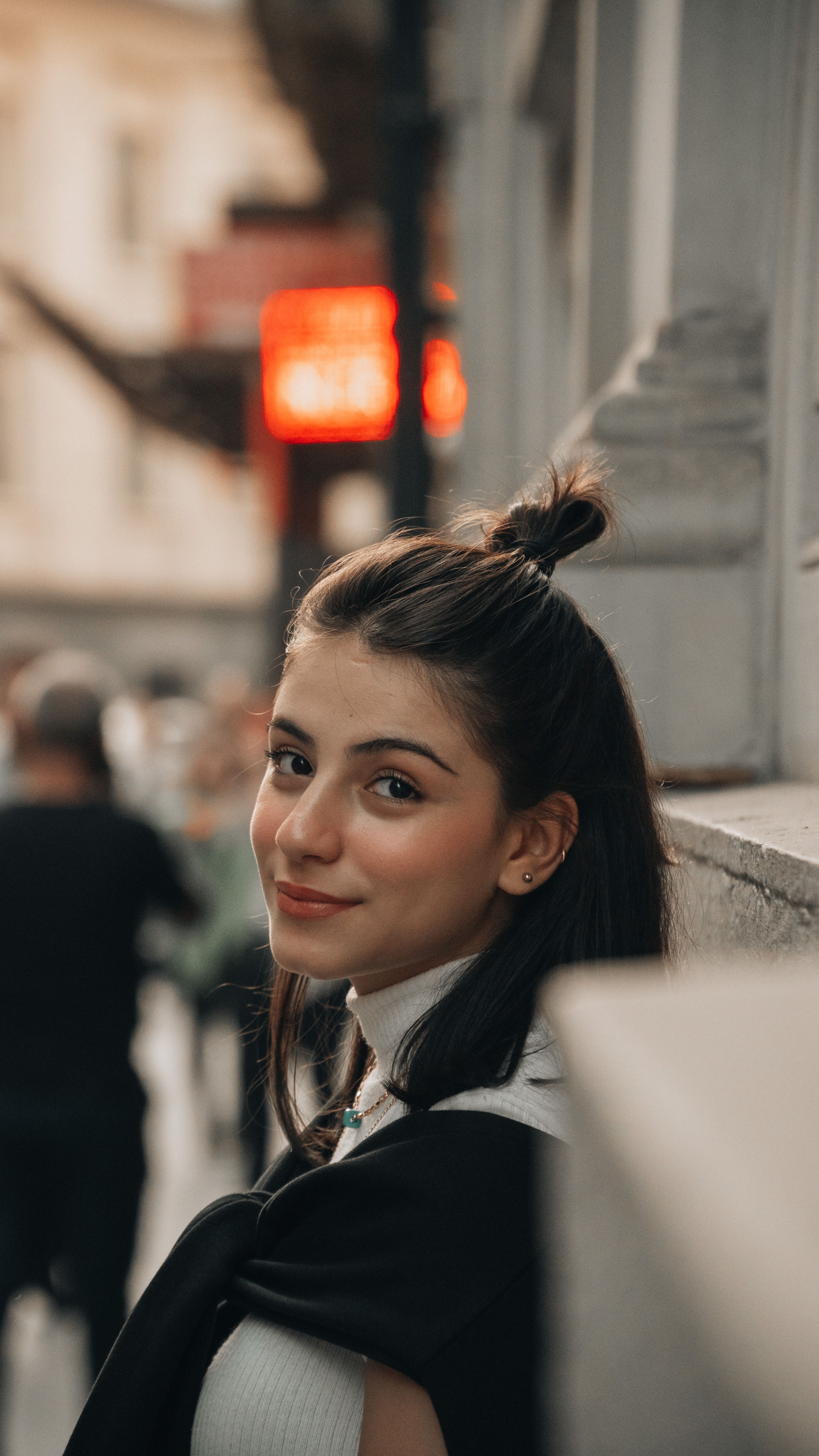 Portrait of a young woman smiling in a city street. Natural light and candid pose.