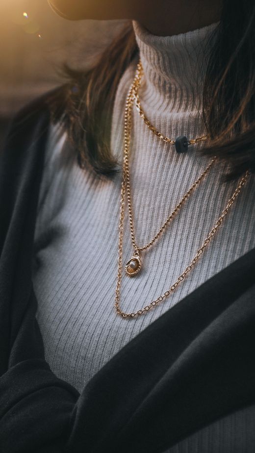 Layered gold chain necklaces worn over a ribbed knit — photo by Gökhan Yetimova on Pexels