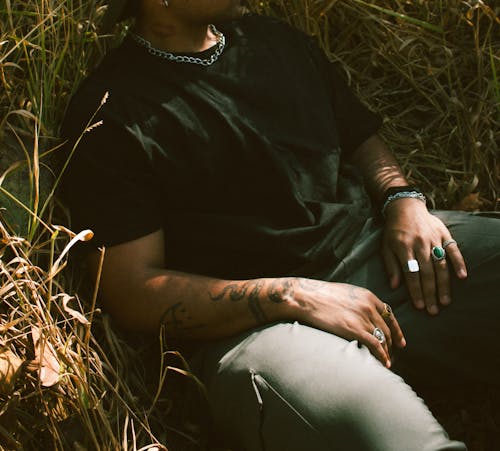 A Man in Black Crew Neck T-shirt and Gray Pants Sitting on a Brown Grass Field