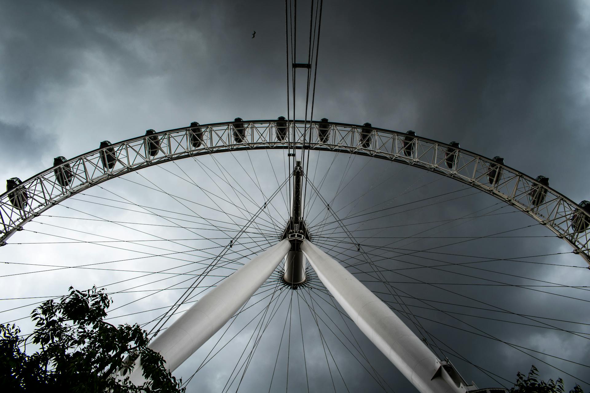 A low-angle shot of the iconic London Eye against a stormy gray sky, highlighting its grandeur.