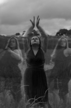 A woman performs a mystical dance in a black and white field, capturing ethereal and ritualistic vibes.