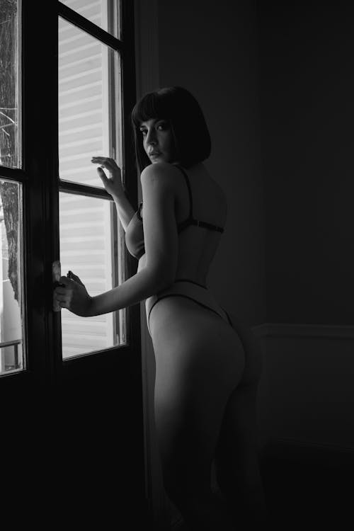 A Woman in Underwear Standing by a Window